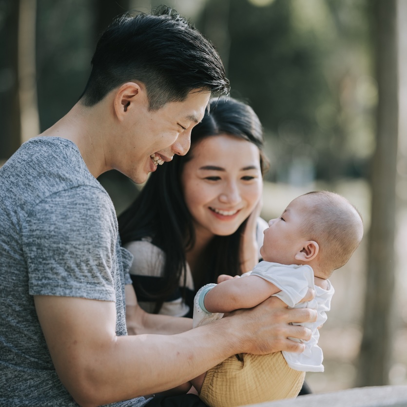 Asian Chinese Parents bonding with their baby boy in public park during weekend morning