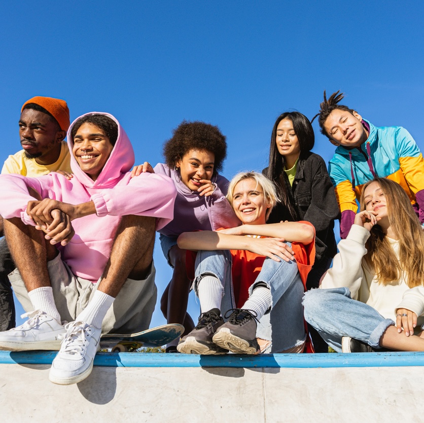 Multicultural group of young friends bonding outdoors and having fun - Stylish cool teens gathering at urban skate park